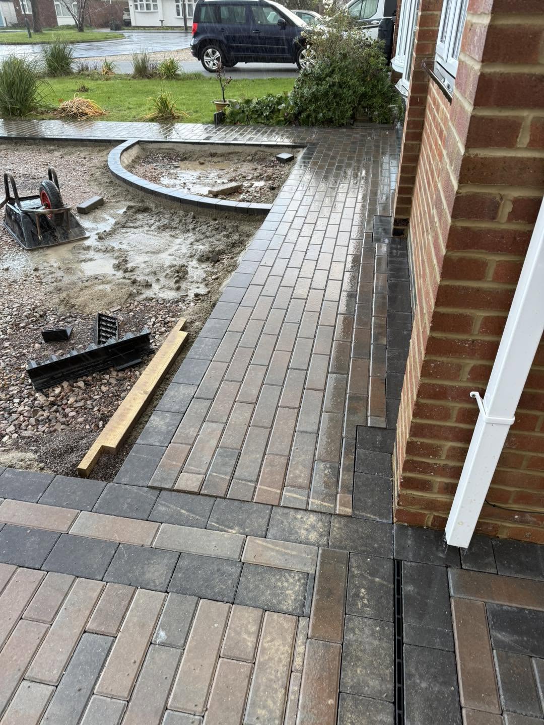 Brindle block paving running along the side of the house with a channel drain
