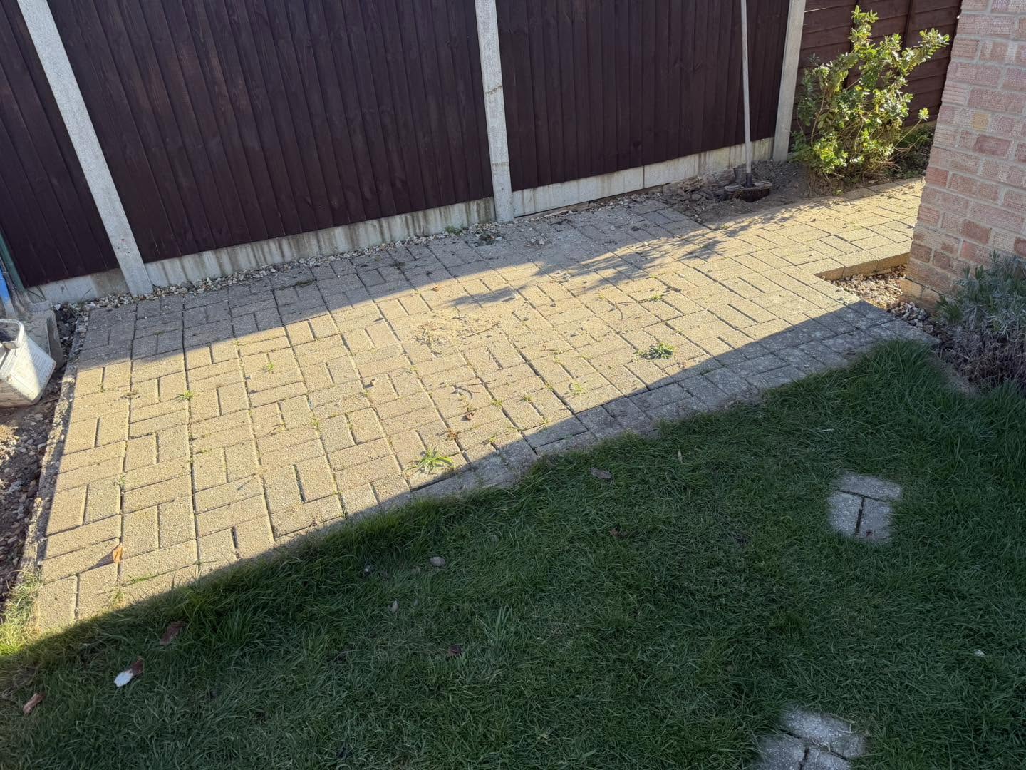 Before: tired buff block paving beside the lawn