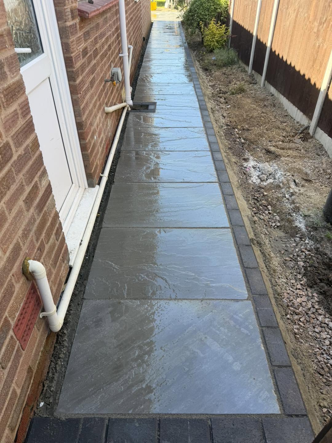 A new grey paved side path with a charcoal block edge