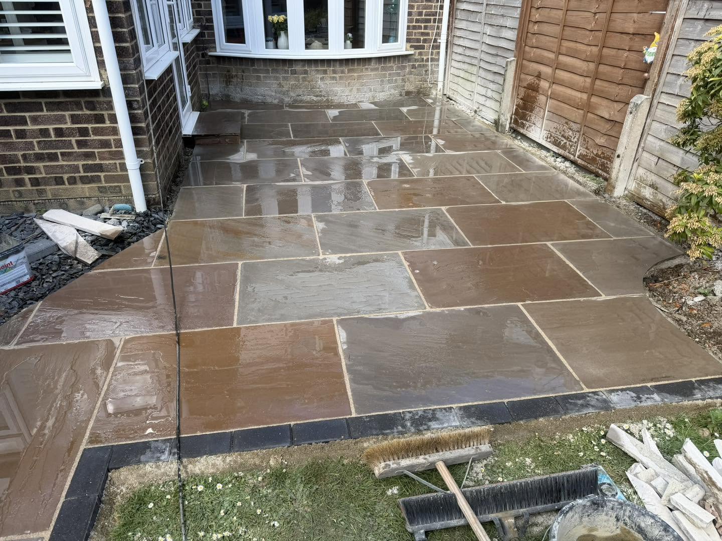 After: a new buff and grey paved patio with a dark block edge