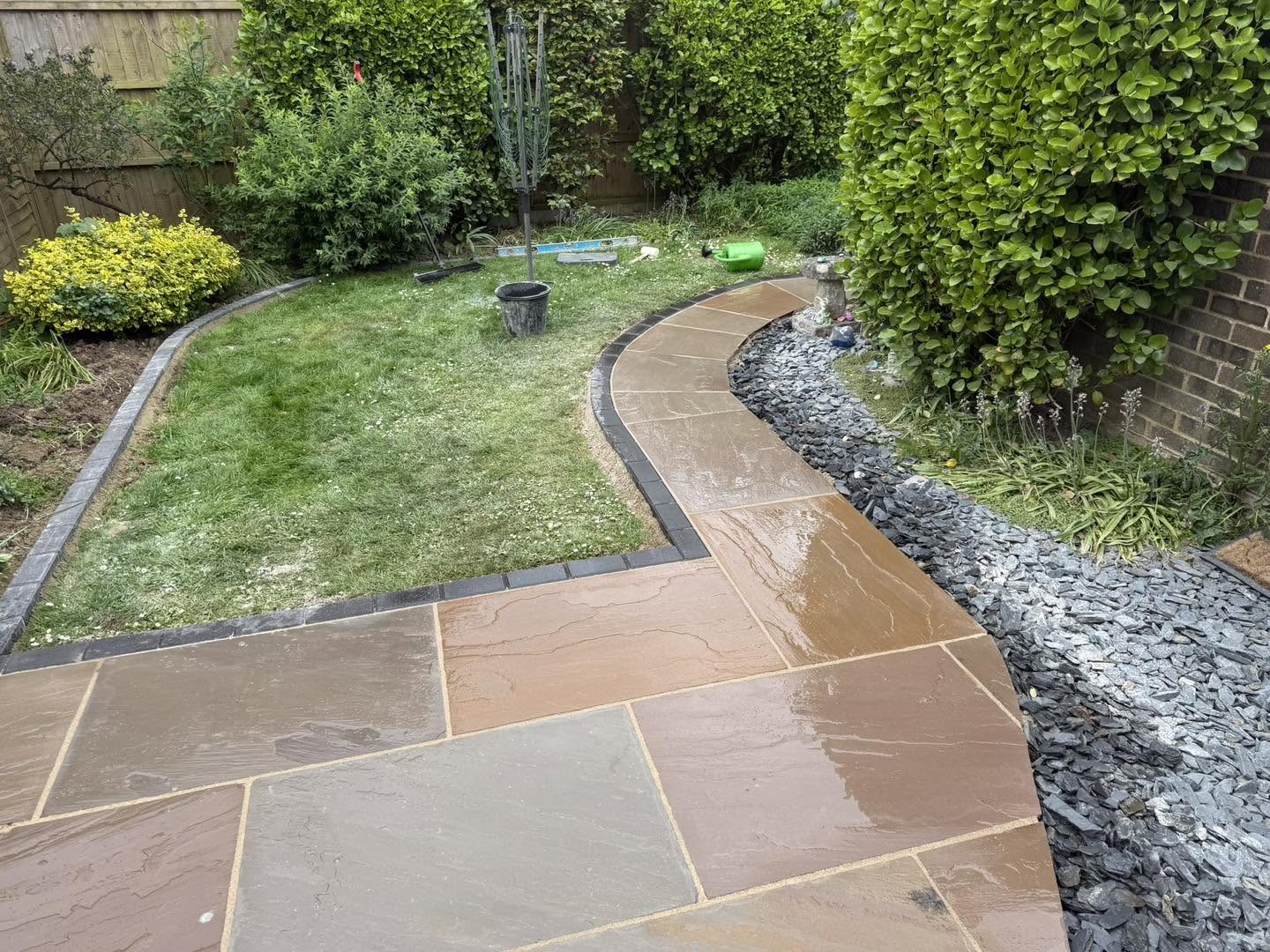 A curving paved path edged in dark blocks beside the lawn