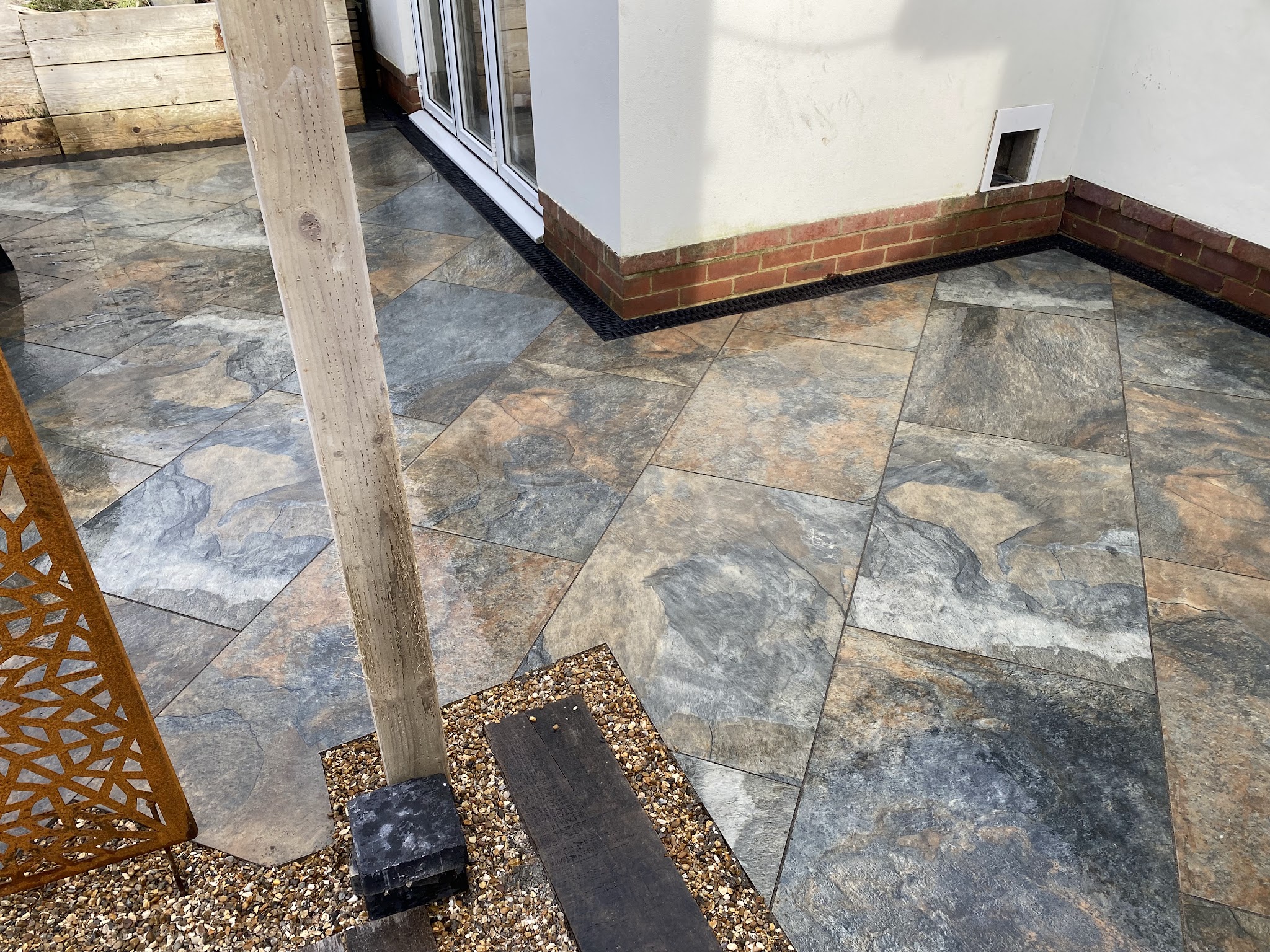A multi-toned slate-effect porcelain patio around a timber post