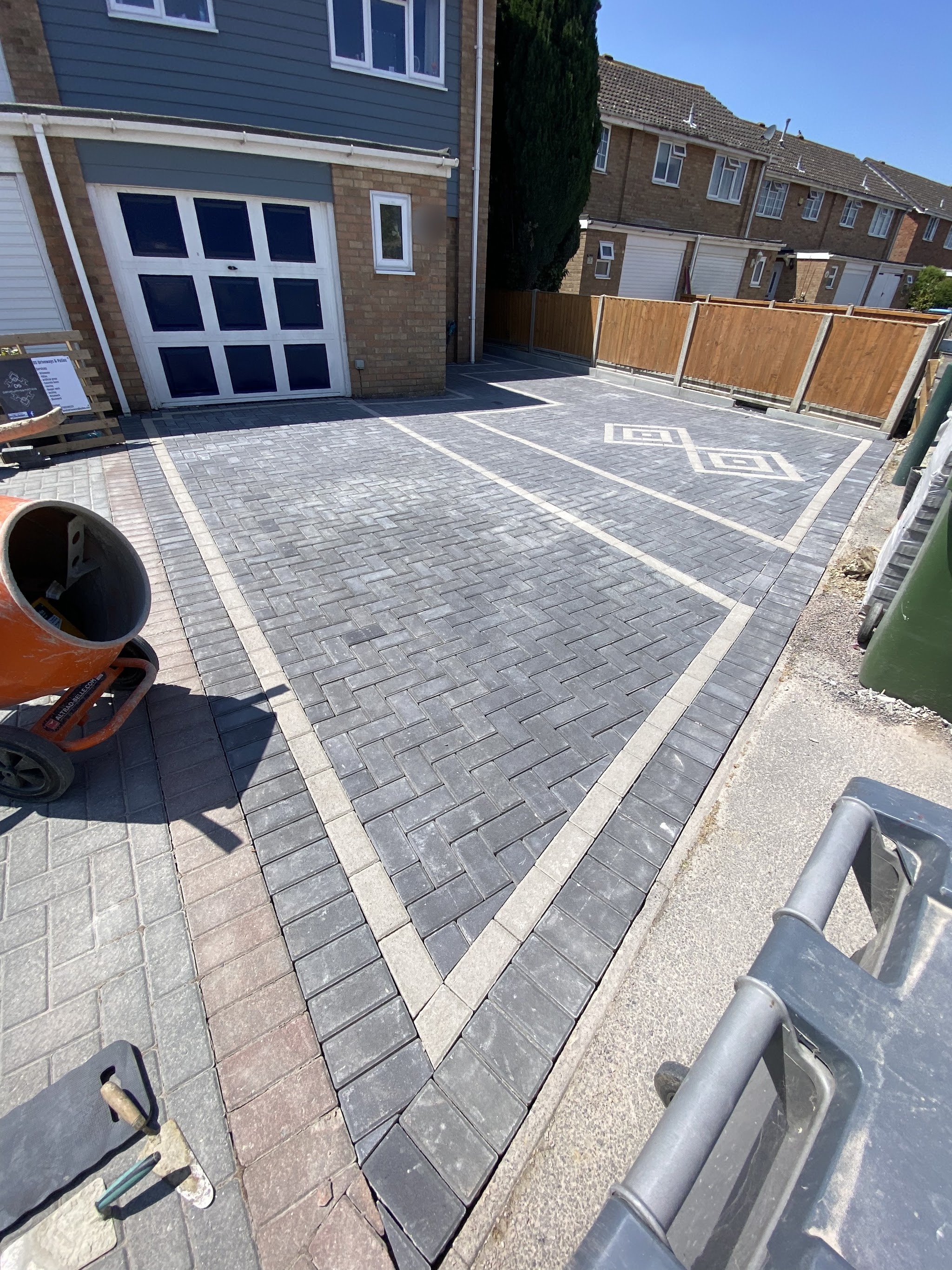 A grey herringbone block-paved driveway with light banding and a diamond inlay