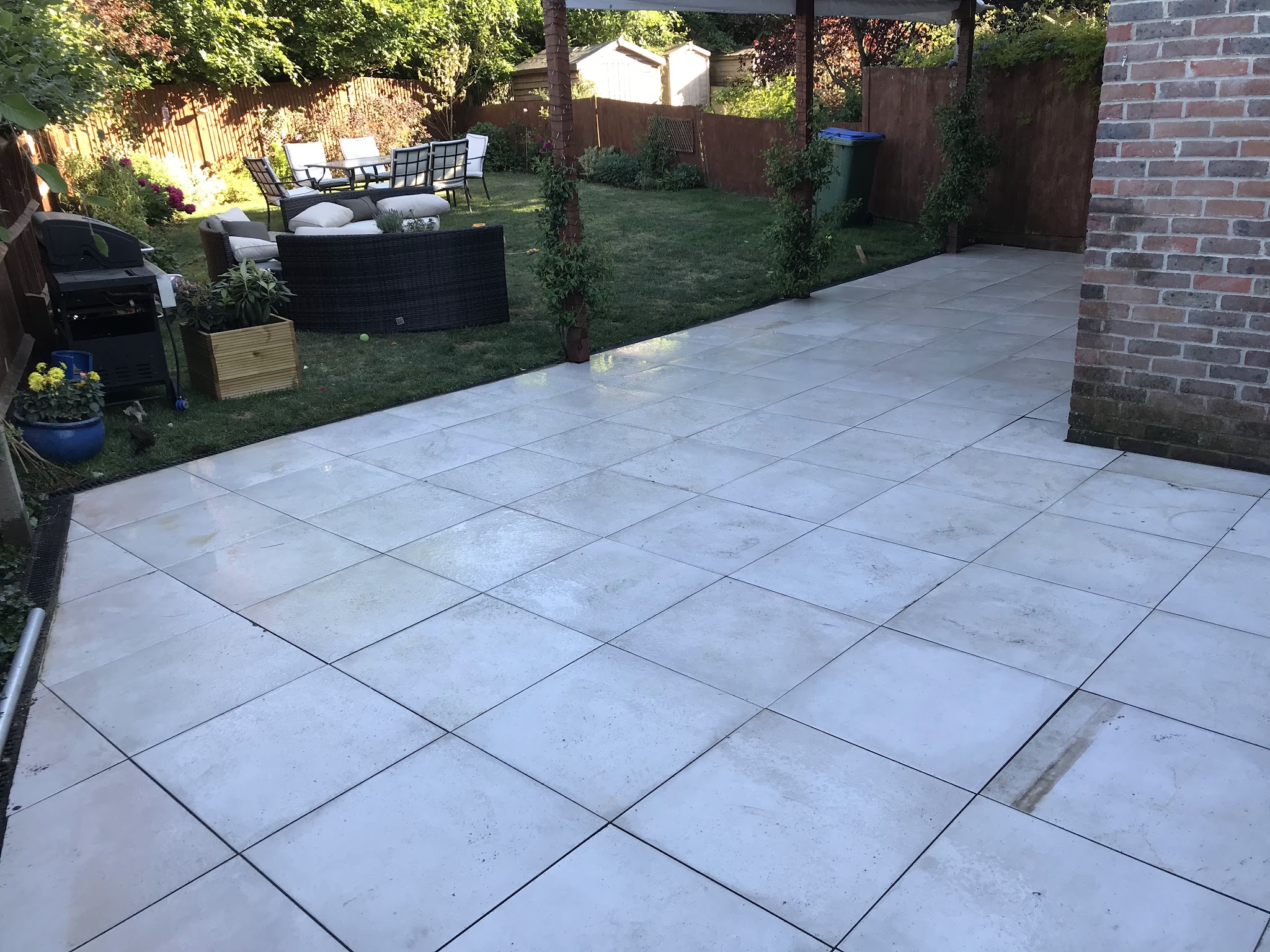 A large light grey porcelain slab patio beside the lawn