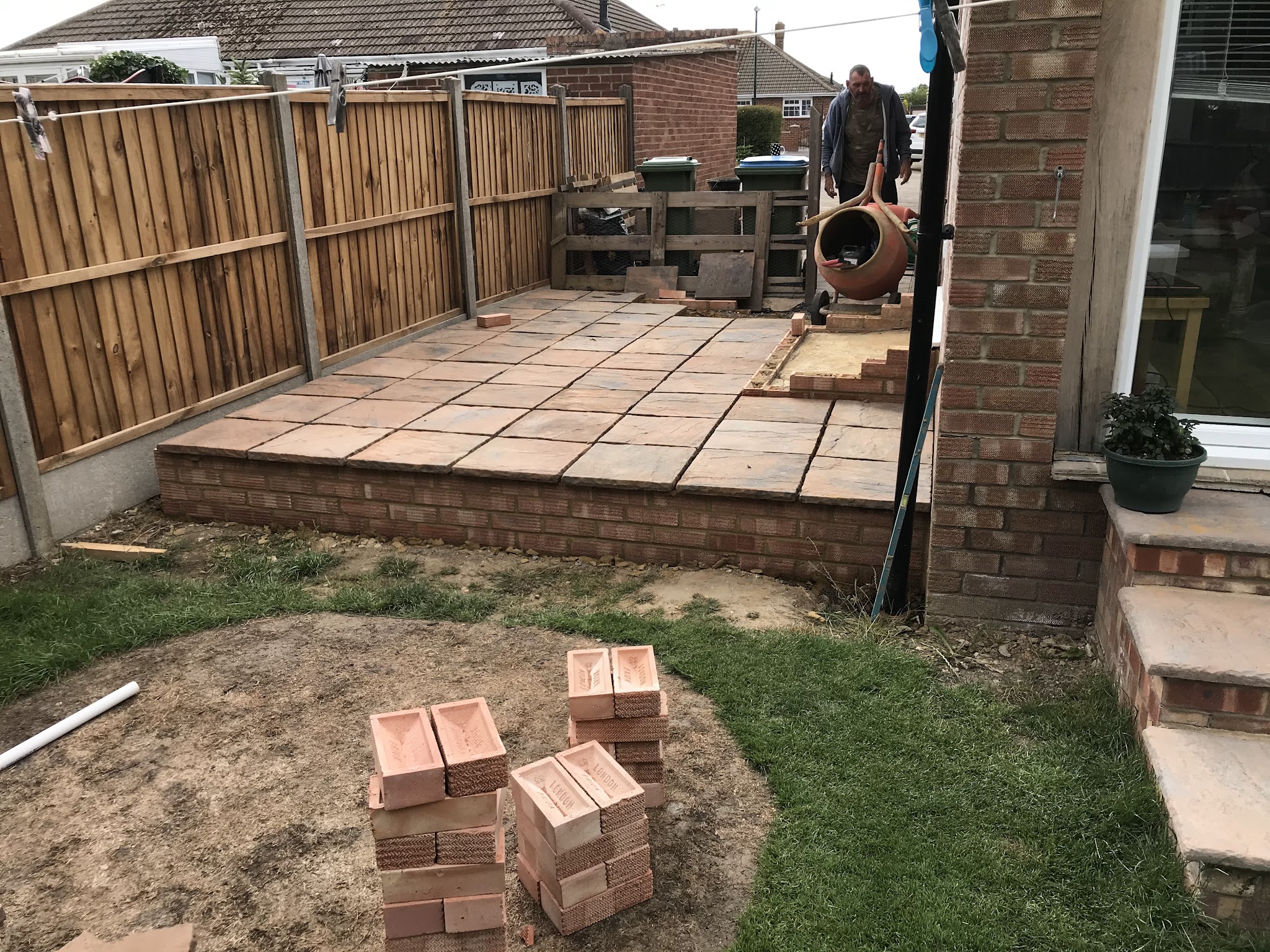 A raised buff paved patio on a brick base with brick steps, work in progress
