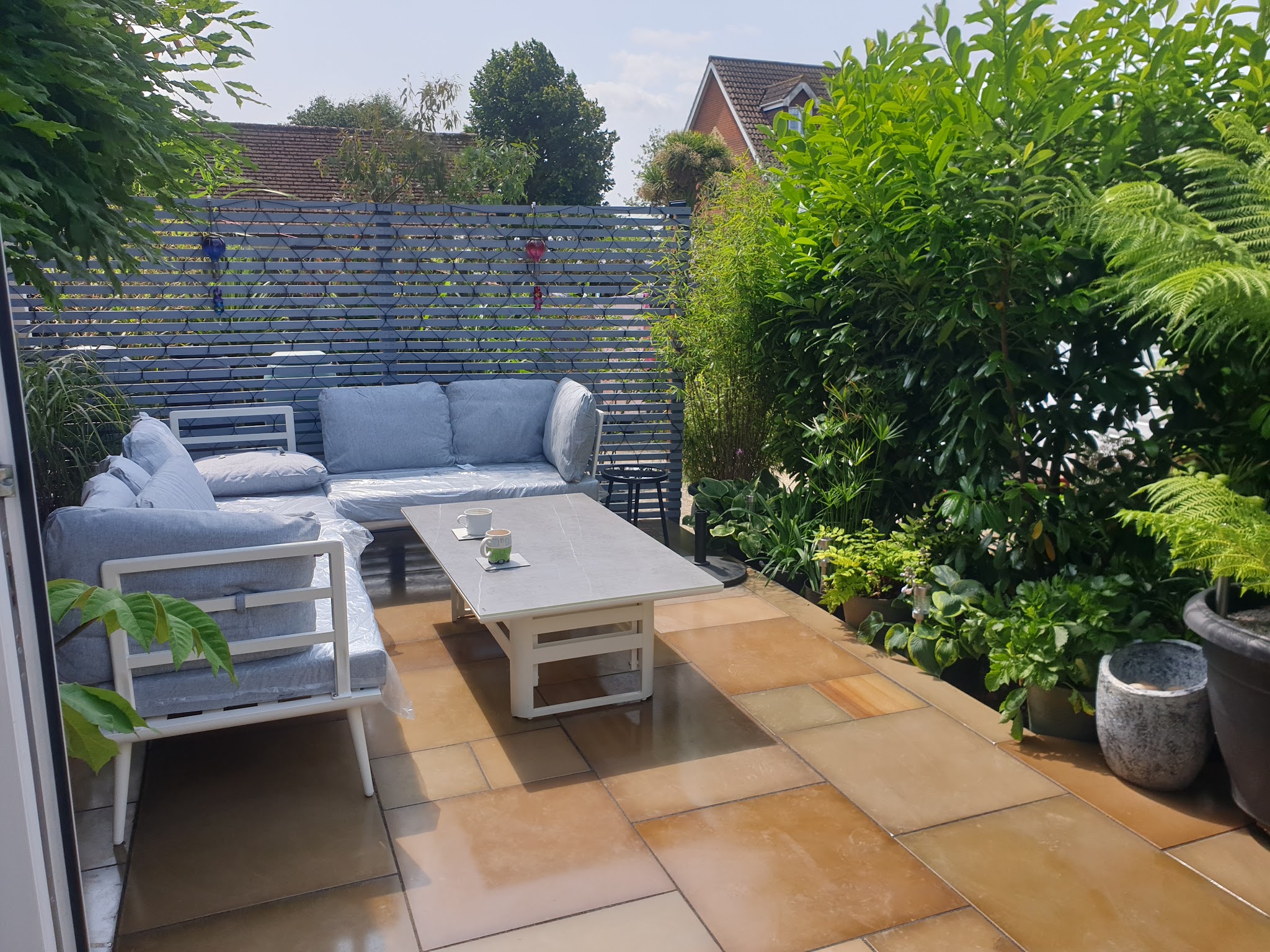 A finished buff paved patio with a garden sofa set and planting